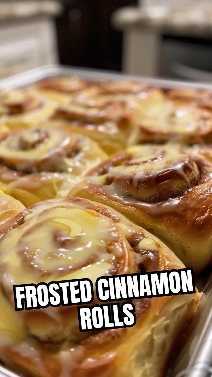 A tray of gooey homemade cinnamon rolls with white icing, fresh from the oven.