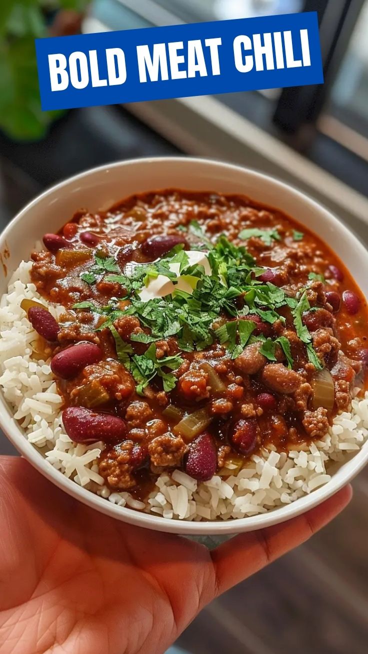 A bowl of rich, red chili con carne garnished with fresh herbs
